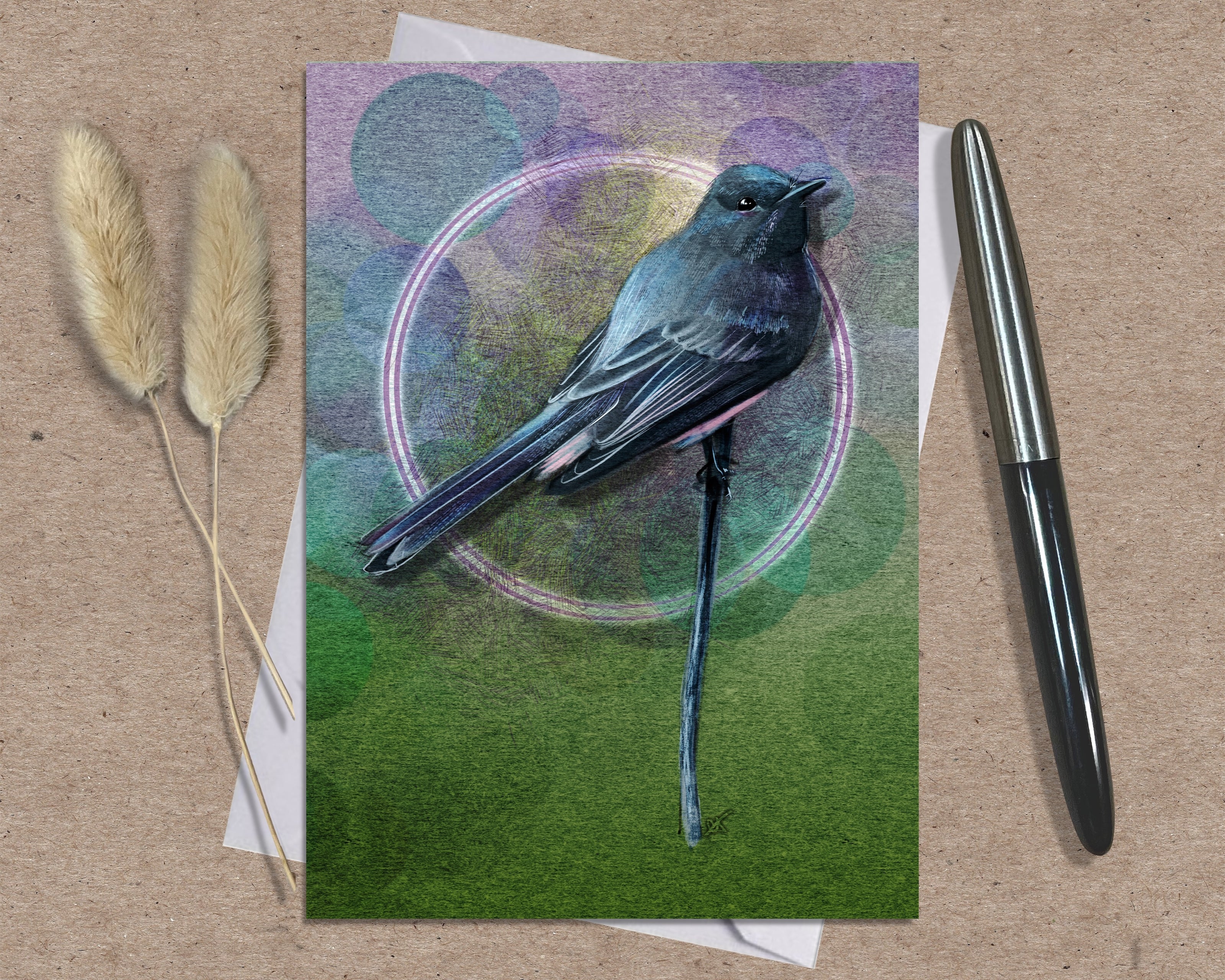 Greeting card with a bird illustration on a textured surface with a pen and dried plants.