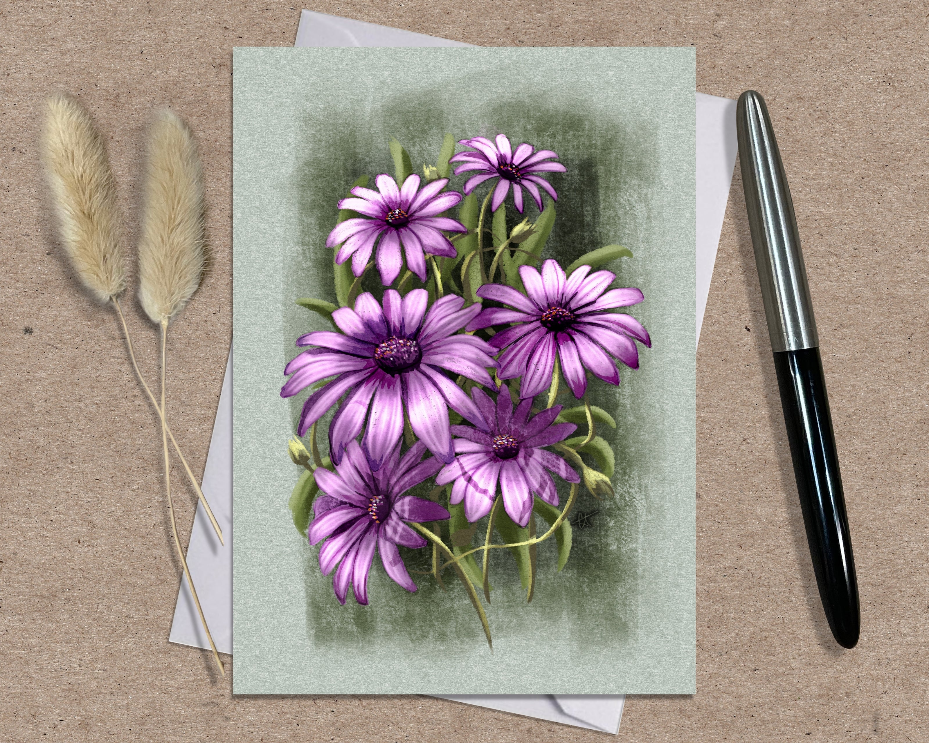 Greeting card with purple flowers on a textured surface with a pen and dried plants.
