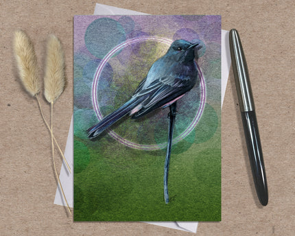 Greeting card with a bird illustration on a textured surface with a pen and dried plants.
