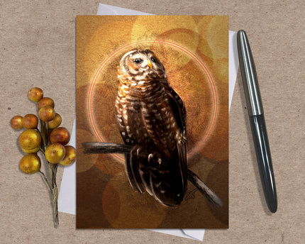 Greeting card with an owl design on a textured surface with a pen and decorative branch.