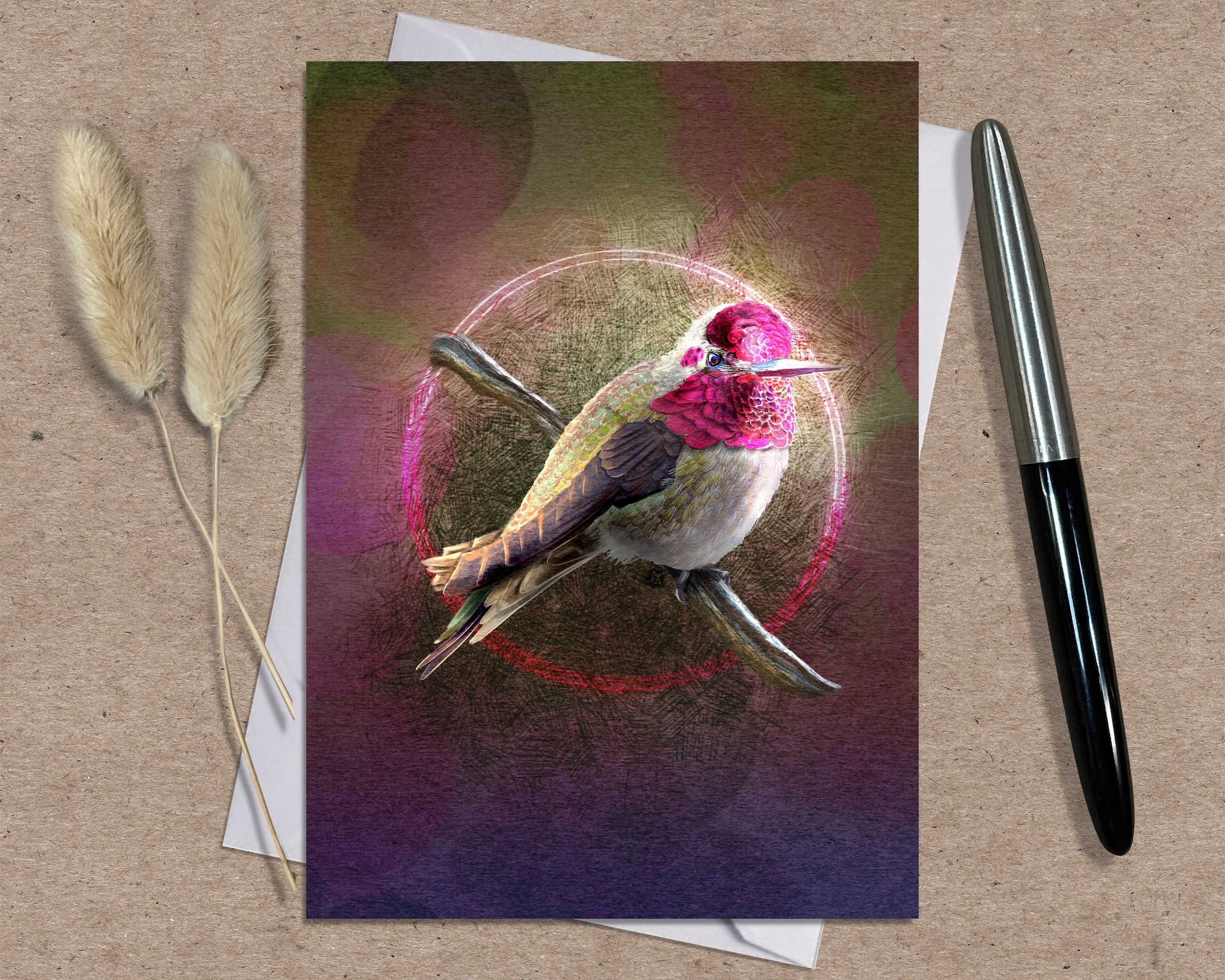 Greeting card with a colorful bird design on a textured surface with a pen and dried plants.