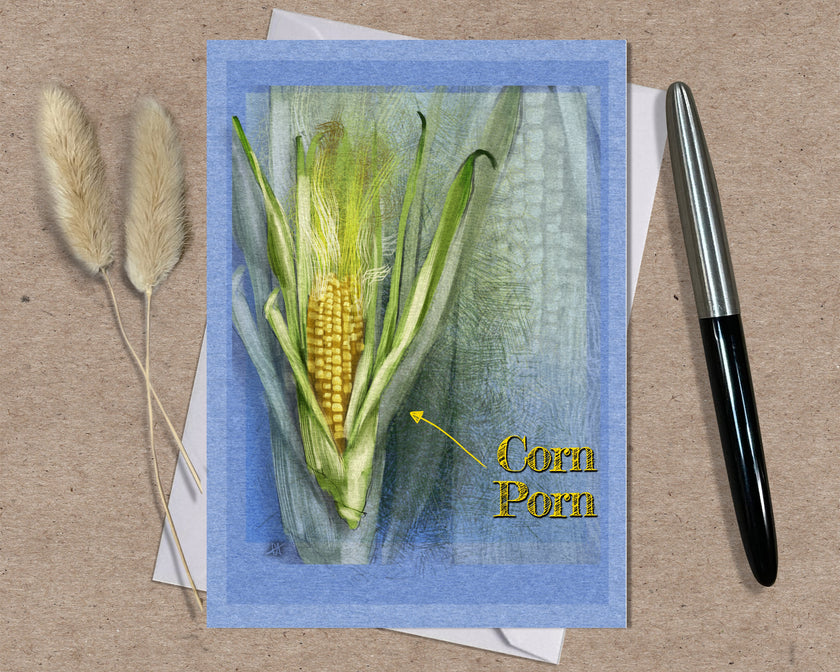 Card with illustration of corn and text 'Corn Porn' on a textured surface with a pen and dried plants.