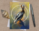 Card with a pelican illustration on a textured surface with a shell and pen.