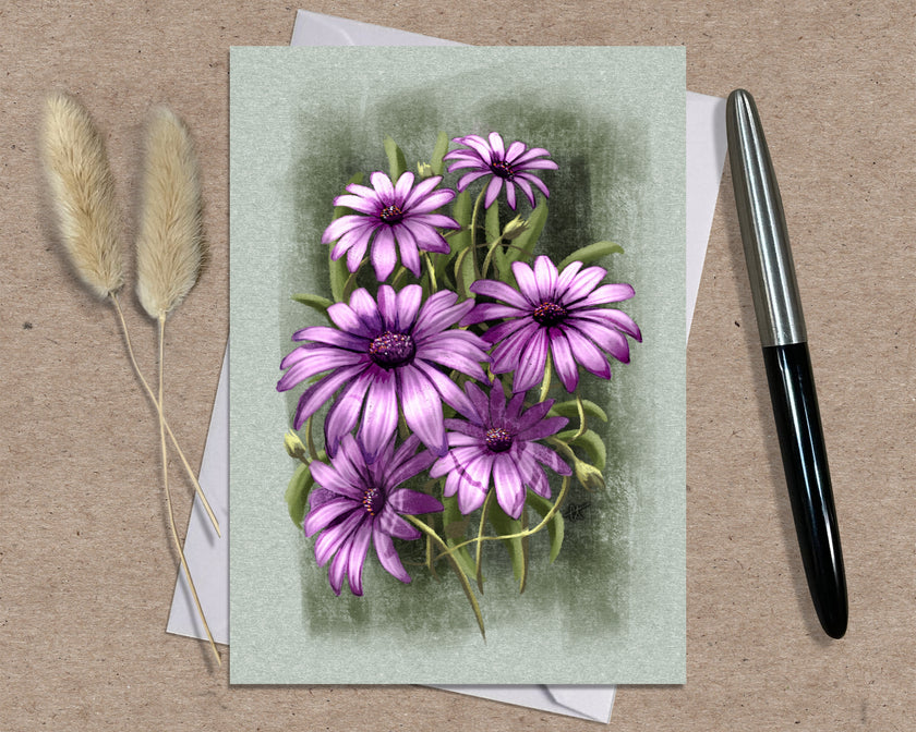Greeting card with purple flowers on a textured surface with a pen and dried plants.